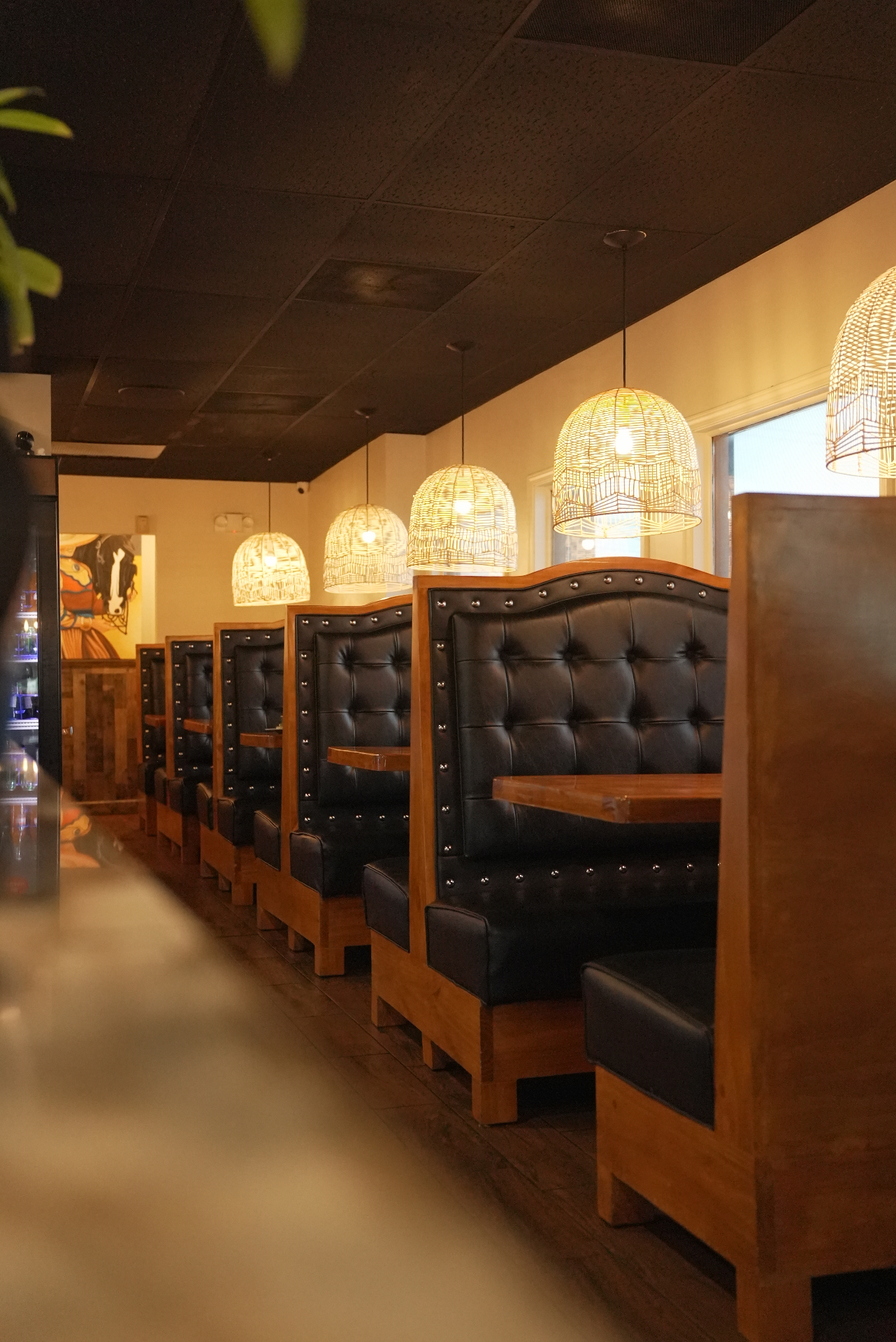 Row of leather booths under woven pendant lights at Chela's